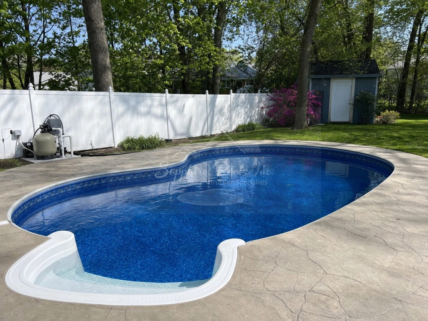 Small oval backyard pool with white fence, visible filter equipment, and steps