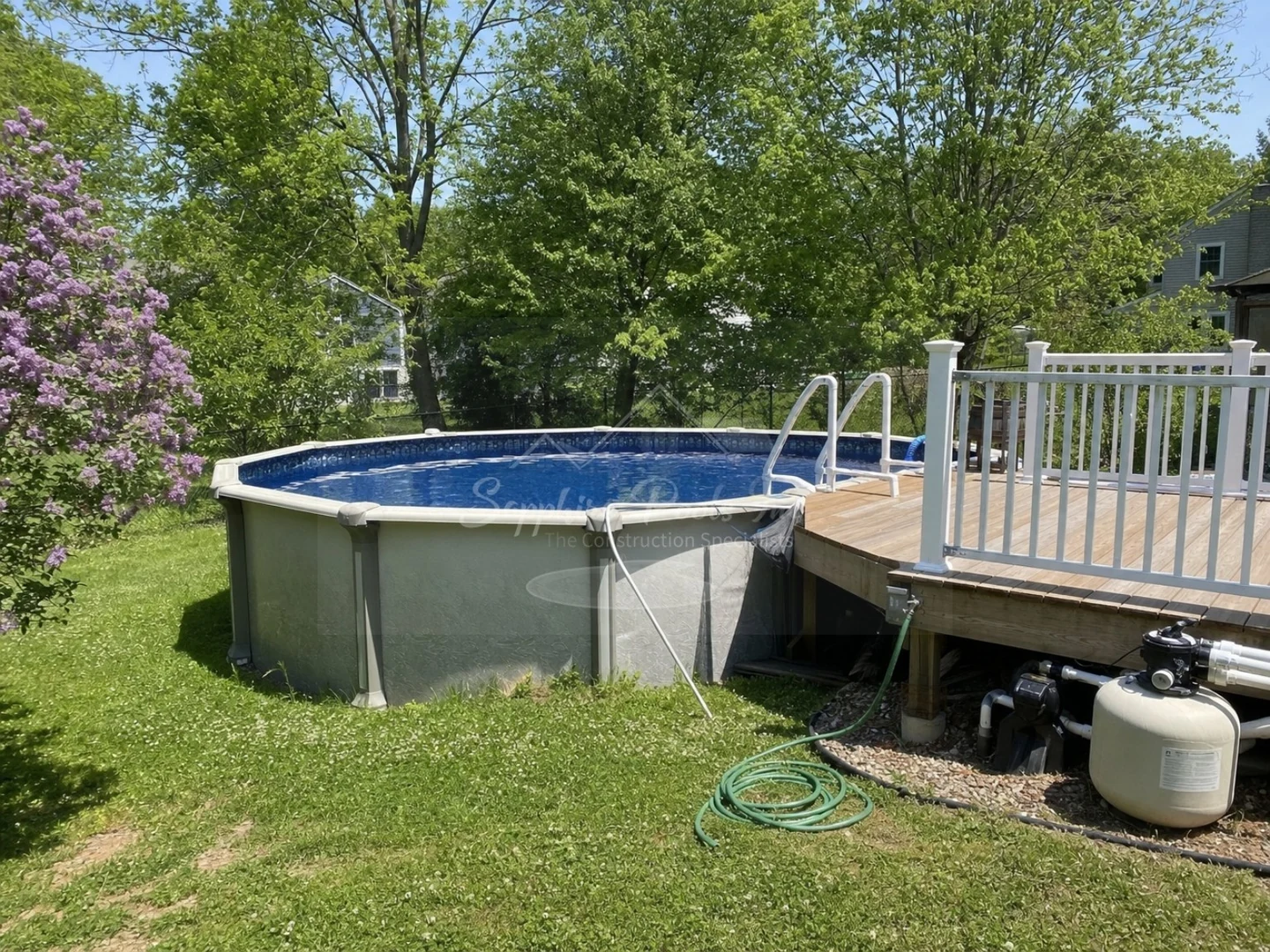 Above-ground circular pool connected to a wooden deck and visible pump equipment